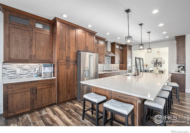 kitchen featuring high quality fridge, wall chimney range hood, a sink, recessed lighting, and dark wood-type flooring