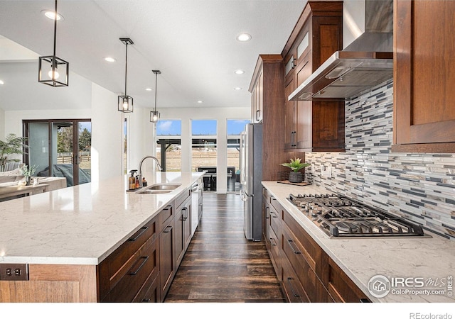 kitchen featuring wall chimney range hood, a sink, stainless steel appliances, plenty of natural light, and recessed lighting