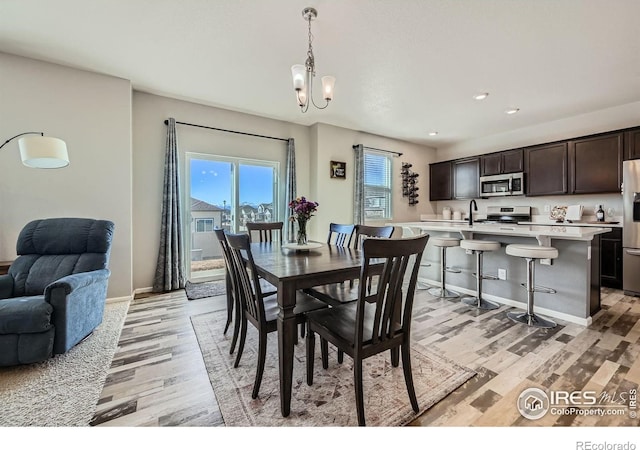 dining area featuring light wood finished floors, baseboards, recessed lighting, and a notable chandelier