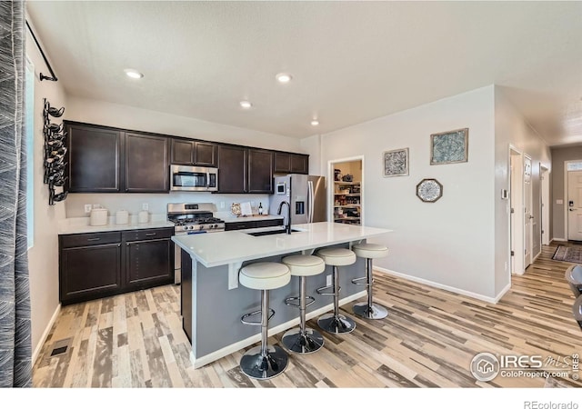 kitchen with baseboards, light wood-style floors, and appliances with stainless steel finishes