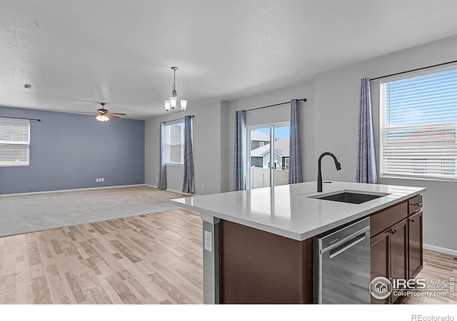 kitchen featuring dishwasher, a sink, light countertops, and light wood-type flooring