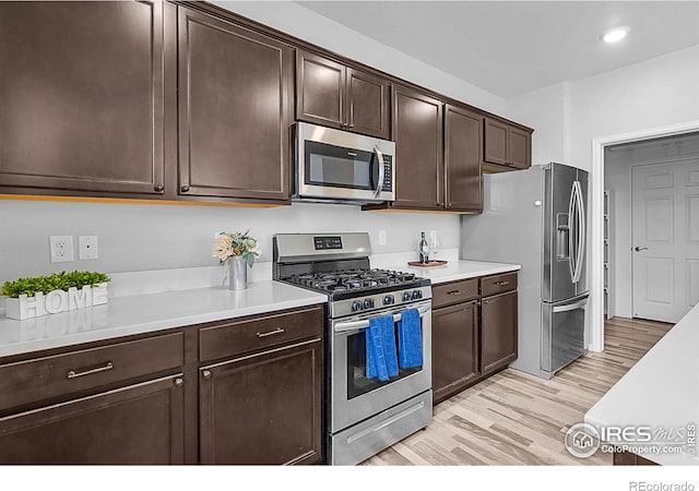 kitchen featuring dark brown cabinetry, appliances with stainless steel finishes, light wood finished floors, and light countertops