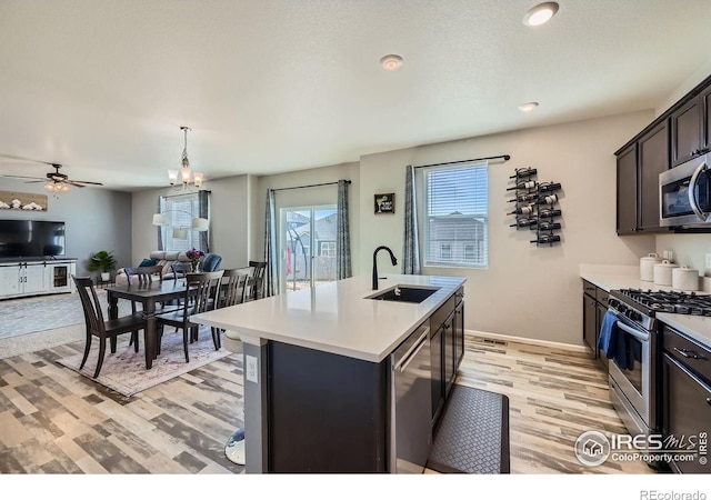 kitchen with light countertops, light wood-style flooring, stainless steel appliances, and a sink