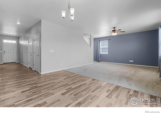 unfurnished living room featuring recessed lighting, light wood-type flooring, baseboards, and ceiling fan with notable chandelier
