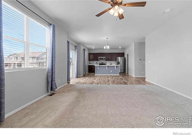 unfurnished living room featuring ceiling fan, baseboards, and light carpet