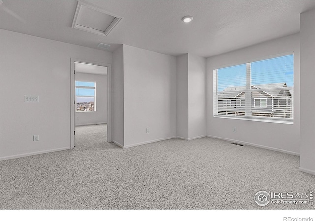 unfurnished room featuring attic access, carpet floors, visible vents, and baseboards