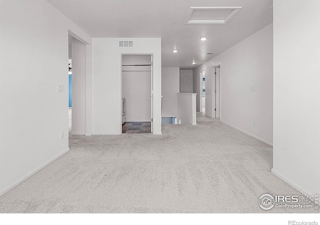 unfurnished bedroom with carpet, a spacious closet, visible vents, baseboards, and attic access