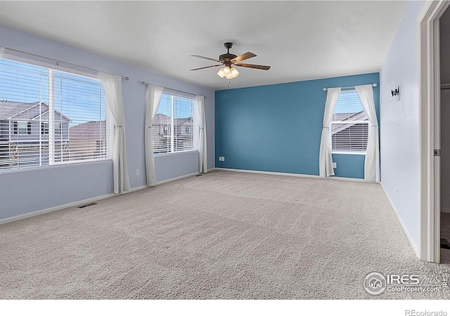 carpeted empty room with ceiling fan, baseboards, and visible vents