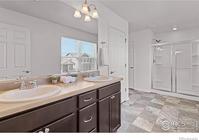 bathroom featuring a chandelier, a sink, double vanity, and a stall shower