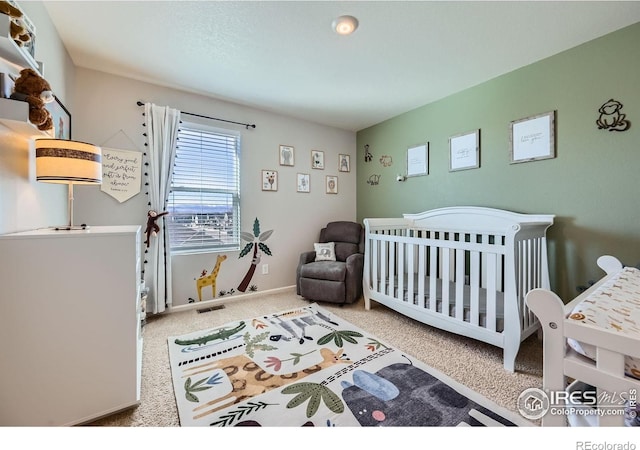 bedroom with carpet, visible vents, and a crib