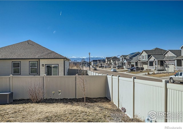 exterior space with central AC unit, fence, and a residential view