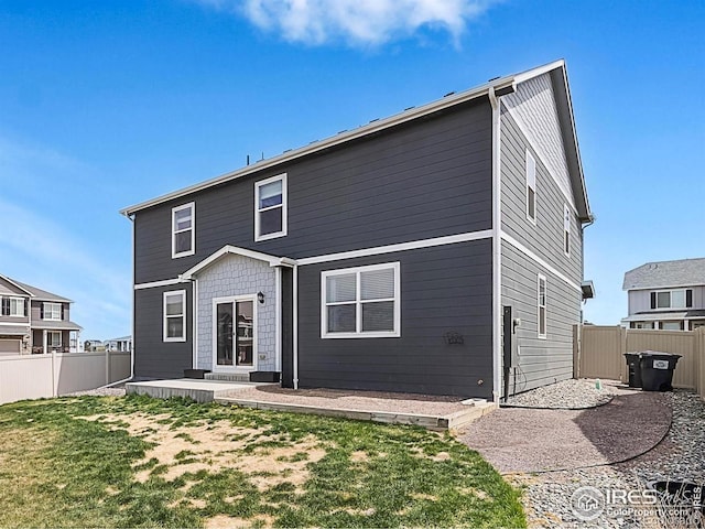 rear view of house featuring a fenced backyard, a yard, and a patio