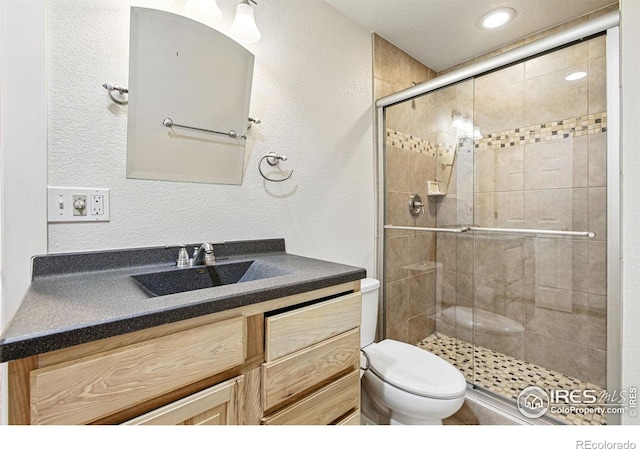 3122 Notabon Ct, Lafayette, CO 80026 - bathroom featuring vanity, toilet, a textured wall, and a stall shower