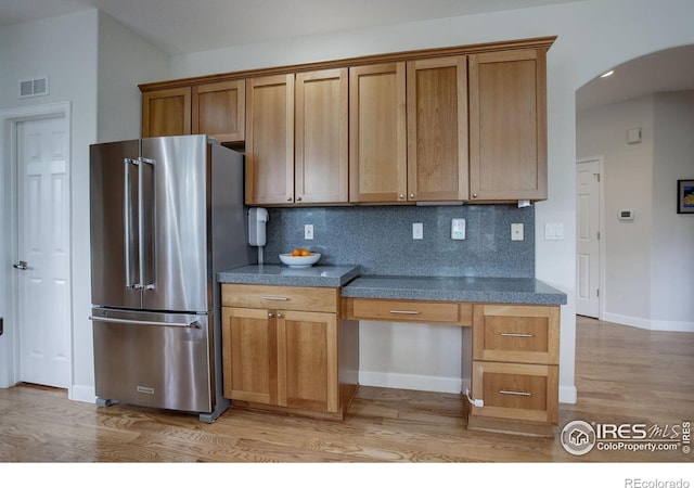 366 Blackhawk Ln, Lafayette, CO 80026 - kitchen featuring freestanding refrigerator, arched walkways, light wood-style floors, dark countertops, and backsplash
