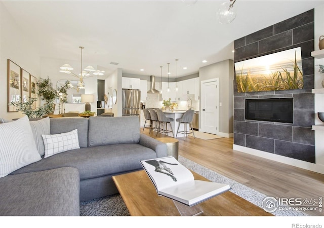 267 Clementina St, Louisville, CO 80027 - living room with recessed lighting, a tile fireplace, baseboards, a chandelier, and light wood-style flooring