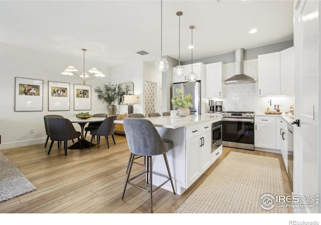 267 Clementina St, Louisville, CO 80027 - kitchen with wall chimney exhaust hood, decorative backsplash, light wood finished floors, and appliances with stainless steel finishes
