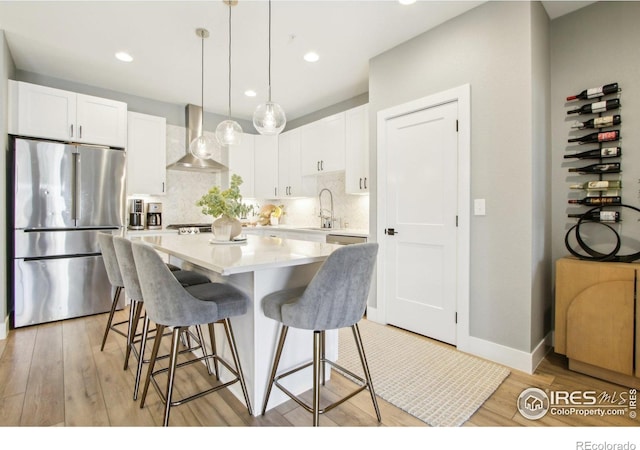267 Clementina St, Louisville, CO 80027 - kitchen with white cabinets, freestanding refrigerator, wall chimney range hood, a kitchen island, and a breakfast bar area