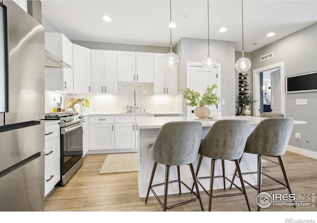 267 Clementina St, Louisville, CO 80027 - kitchen with stainless steel appliances, a sink, a kitchen island, decorative backsplash, and a breakfast bar area