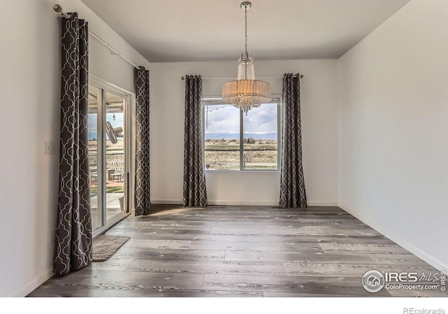 6021 Sandstone Cir, Erie, CO 80516 - unfurnished dining area with baseboards, a wealth of natural light, hardwood / wood-style flooring, and an inviting chandelier