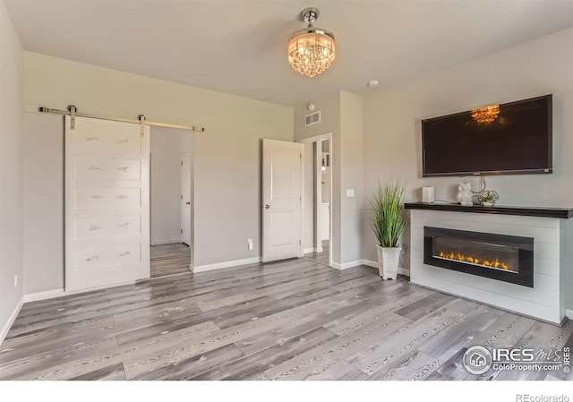 6021 Sandstone Cir, Erie, CO 80516 - unfurnished living room with a barn door, baseboards, light wood finished floors, and visible vents
