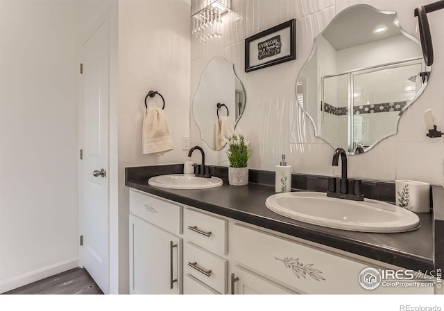 6021 Sandstone Cir, Erie, CO 80516 - bathroom featuring wood finished floors, a sink, double vanity, and a stall shower