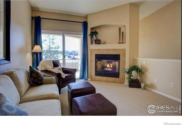 living area featuring baseboards, carpet flooring, and a tile fireplace