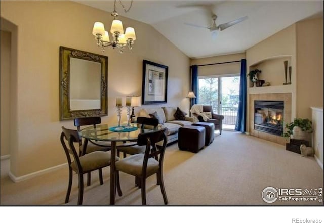carpeted dining area featuring baseboards, a fireplace, ceiling fan with notable chandelier, and lofted ceiling