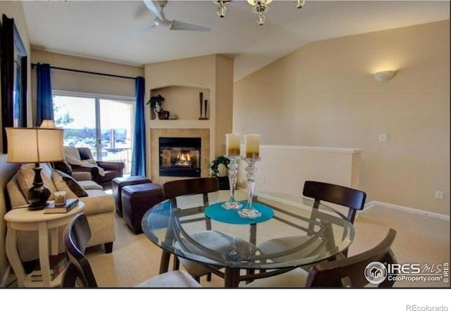 carpeted dining space with baseboards, a tile fireplace, and lofted ceiling