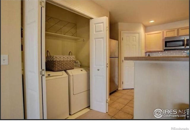 laundry area with laundry area, light tile patterned flooring, and washing machine and clothes dryer