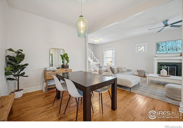 3059 N York St, Denver, CO 80205 - dining room featuring ceiling fan, a glass covered fireplace, stairs, baseboards, and light wood-type flooring