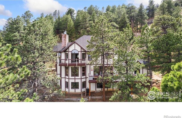 tudor house featuring a chimney and a balcony