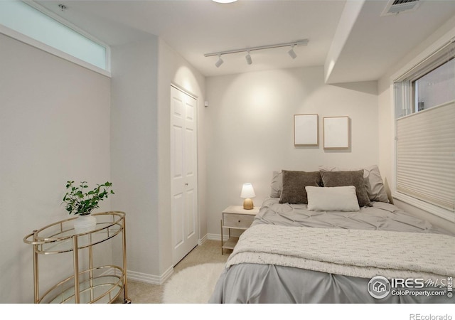 bedroom with light carpet, track lighting, visible vents, and baseboards