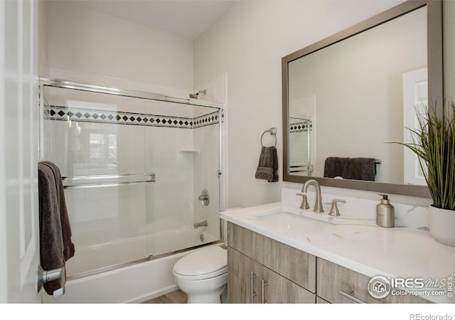 bathroom with shower / bath combination with glass door, toilet, and vanity