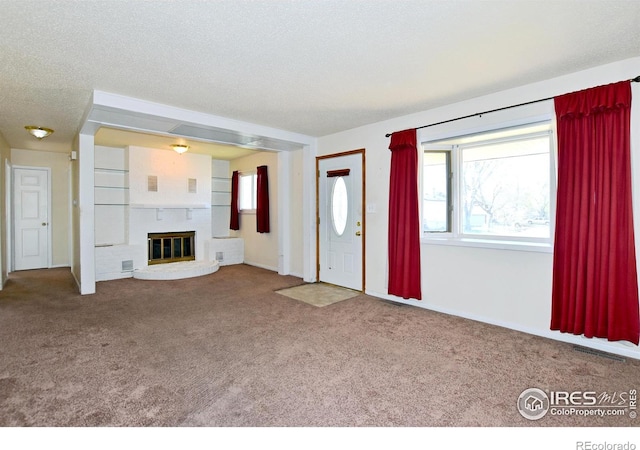 unfurnished living room with a fireplace, a healthy amount of sunlight, visible vents, and carpet
