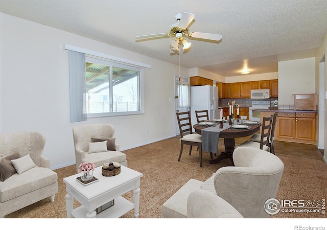 carpeted living room featuring ceiling fan and baseboards