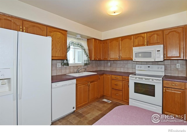 kitchen featuring brown cabinets, backsplash, a sink, and white appliances