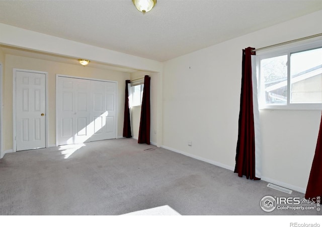 unfurnished bedroom featuring baseboards, visible vents, carpet floors, and a closet