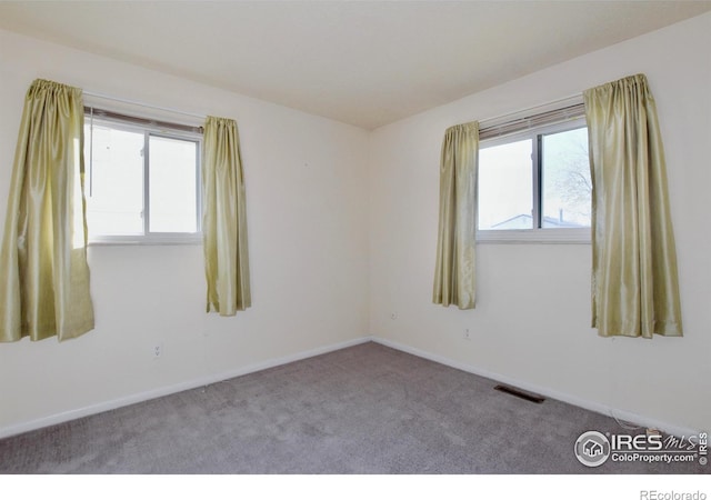 carpeted empty room with plenty of natural light, visible vents, and baseboards