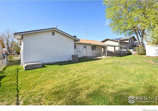 rear view of house with fence and a lawn