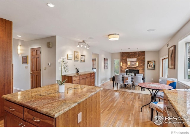 5285 Gallatin Pl, Boulder, CO 80303 - kitchen with light wood finished floors, baseboards, light stone counters, brown cabinetry, and a fireplace