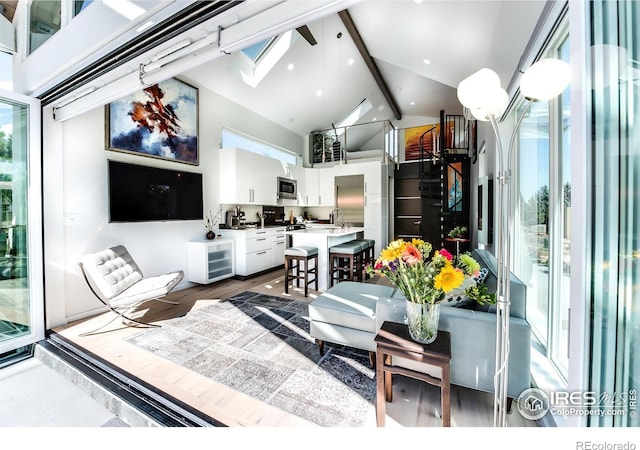 living area featuring high vaulted ceiling, beam ceiling, dark wood-type flooring, and a skylight