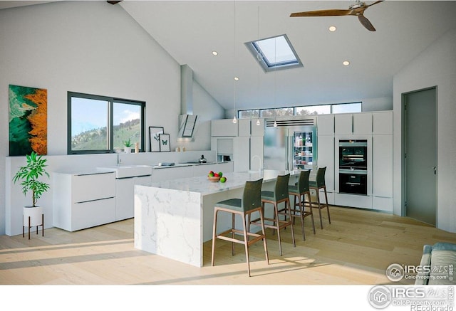 kitchen with a spacious island, a skylight, modern cabinets, ceiling fan, and high vaulted ceiling
