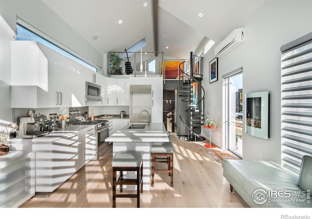 kitchen featuring white cabinets, a sink, light wood-style flooring, appliances with stainless steel finishes, and high vaulted ceiling