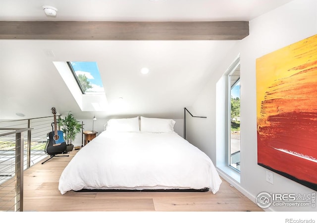 bedroom featuring wood finished floors, vaulted ceiling with skylight, and multiple windows