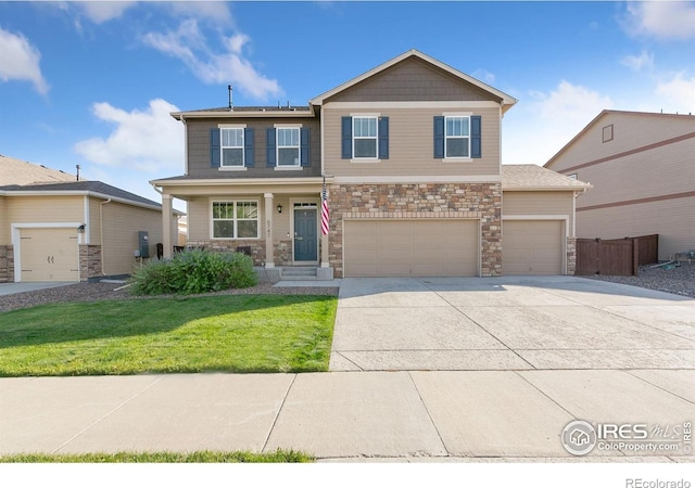 craftsman inspired home featuring fence, a front yard, stone siding, an attached garage, and driveway