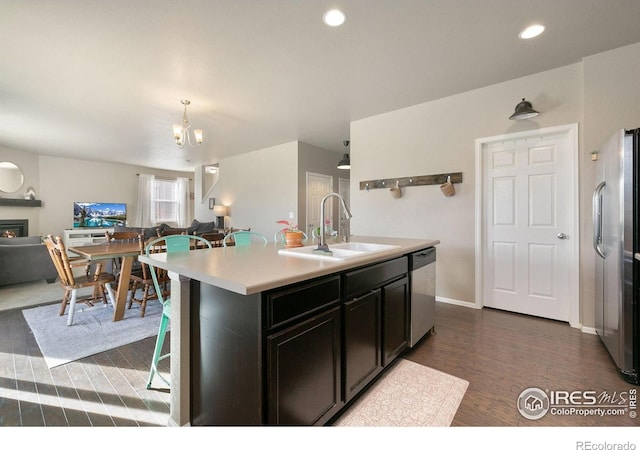 kitchen featuring appliances with stainless steel finishes, a sink, light countertops, dark wood finished floors, and open floor plan