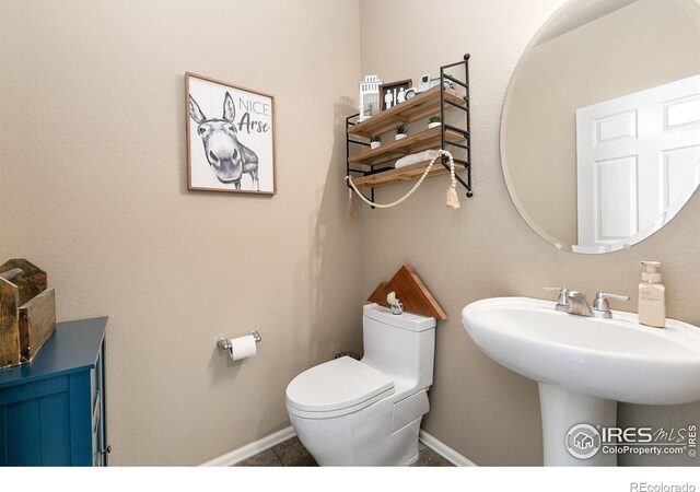half bath with a sink, baseboards, and toilet