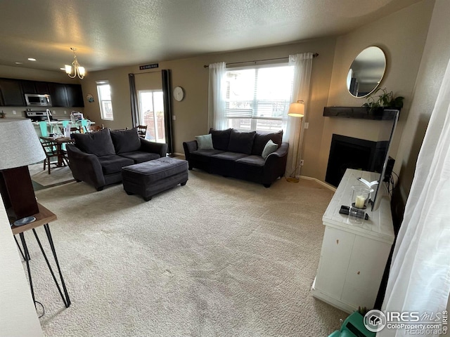 living area with light colored carpet, a textured ceiling, a fireplace, and an inviting chandelier