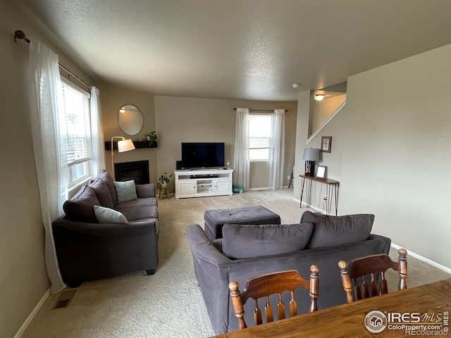 living room with visible vents, baseboards, a fireplace, and light carpet