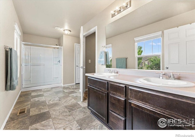 6747 Grainery Rd, Timnath, CO 80547 - full bathroom featuring baseboards, a stall shower, double vanity, and stone finish flooring